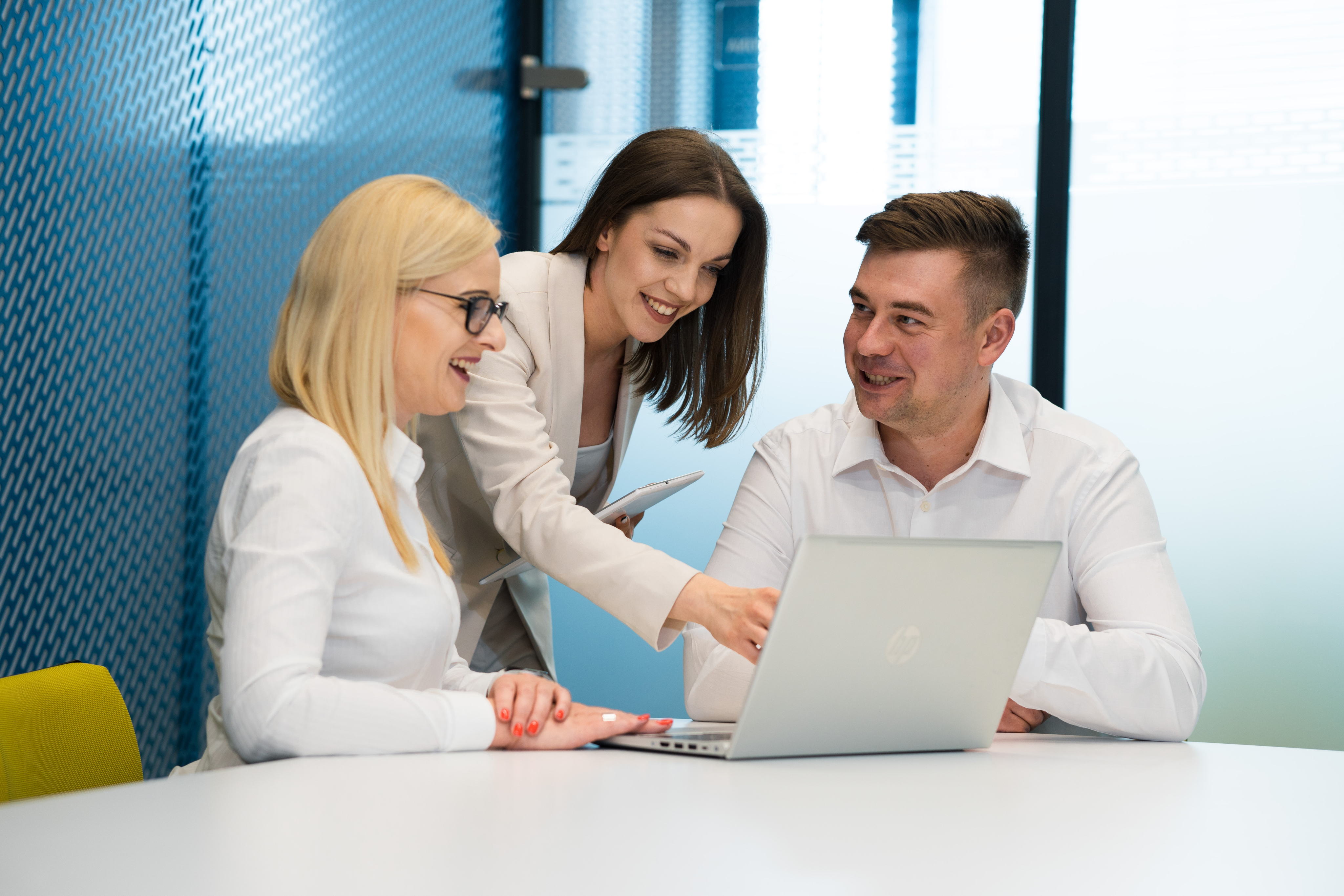 Three marketing specialists looking at the screen of a laptop and sharing a happy moment.